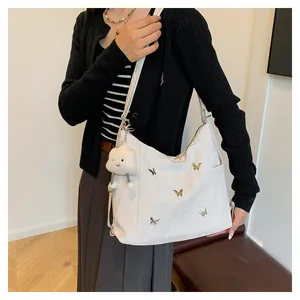 Détail du sac hobo blanc avec décorations de papillons dorés et charm de nuage