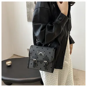 Detail of grey polka dot backpack with silver bow hardware and black leather trim accents