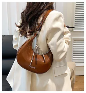 Detail of a brown glossy hobo bag featuring silver bead chain and Fashion logo detail