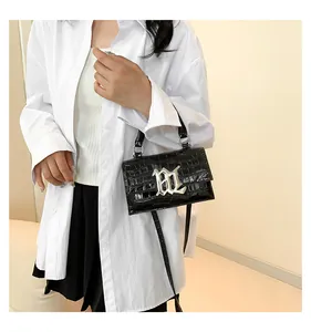 Details einer schwarzen Handtasche mit Kroko-Prägung, silbernem Logo und Rundgriff