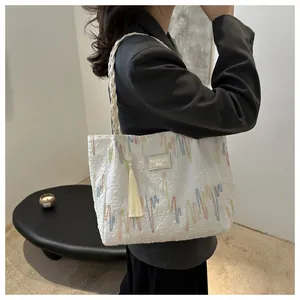 Detail of white tote bag with colorful wave patterns and braided strap on a model