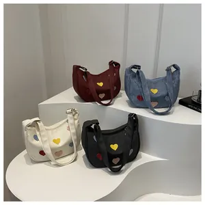 Detailed view of four colorful crescent underarm bags with heart patterns on white steps