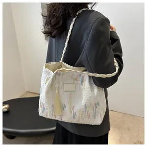 Detailed shot of a white woven tote bag featuring colorful wavy embroidery and long tassels