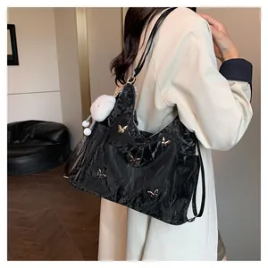 Détail du sac cabas plissé noir avec papillons dorés et breloque ours en peluche