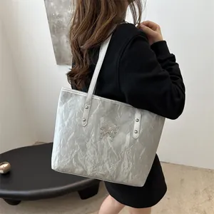 Silver metallic pleated tote bag with butterfly detail shown as a shoulder bag