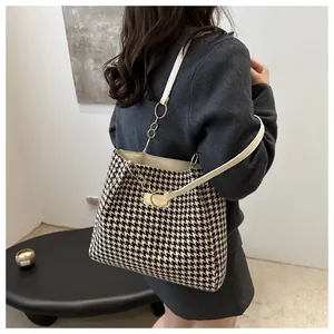 Gros plan d'un sac cabas à motif pied-de-poule avec bandoulière en cuir crème