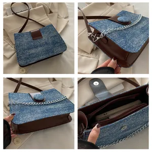 Detailweergave van denim schoudertas met lederen riemen, kettingen en compartimenten