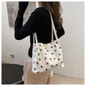 Détail du cabas en velours côtelé blanc avec imprimé fraise rouge et texture côtelée