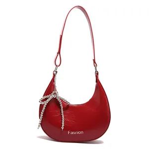 Bright red crescent crossbody bag in glossy leather with silver beaded bow ornament