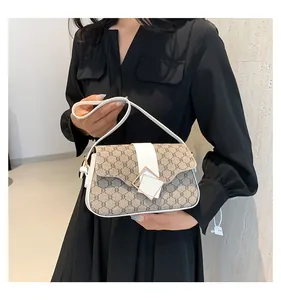 Nahaufnahme einer kleinen quadratischen Handtasche mit Monogramm und weißem Besatz