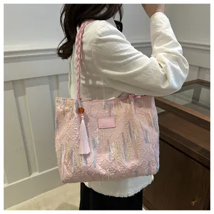 Detail of pink tote bag with geometric texture, colorful embroidery and tassel charm