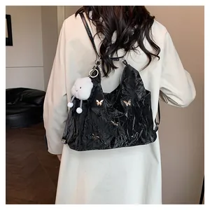 Détail du sac cabas plissé noir brillant avec papillon argenté et breloque nuage