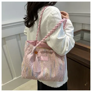 Close-up of pink jacquard tote bag with fringe details and beaded tassel accessory