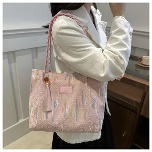 Detail of pink quilted tote bag with colorful embroidery and elegant silk tassel