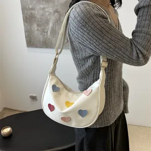 Chic white crescent shoulder bag with colorful heart patches and adjustable strap