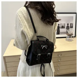Detail of black mini backpack with red heart embroidery and silver bow ornament on flap