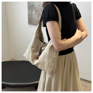 Detailed texture of beige hobo bag with white bamboo leaf patterns and beaded knot