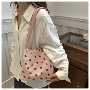 Détail du sac fourre-tout en velours rose avec imprimé fraise et bandoulière confortable