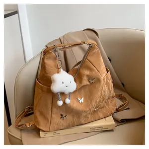 Détail du sac plissé kaki avec des papillons argentés et un porte-clé en forme de nuage