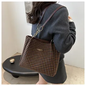 Détail du sac cabas en pied-de-poule avec chaînes dorées élégantes et texture de tissu premium