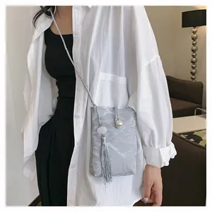 Détail du mini sac bandoulière gris orné d'une perle et d'un pompon fleur blanche chic