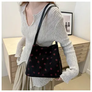 Détail du sac fourre-tout en velours noir avec broderie de fraises et fines lanières
