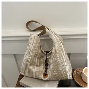 Detail of pleated tote bag with bamboo leaf pattern and amber pendant decoration