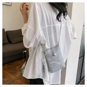 Détail d'un mini sac à bandoulière gris marbré avec fermoir perle et pompon en soie