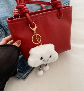 Dettaglio borsa a secchiello rossa trama litchi con ciondolo peluche nuvola bianca