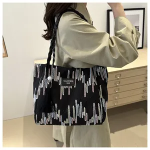 Detail of black fabric tote bag featuring abstract embroidery and beaded tassel charm