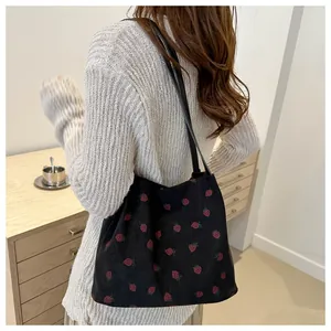 Détail d'un grand sac cabas en velours côtelé avec imprimé fraise porté à l'épaule