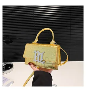 Detail der gold metallic Handtasche mit Krokodilprägung und silbernem B-Buchstabenverschluss
