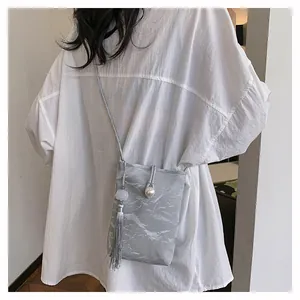 Détail du mini sac gris texturé avec fermoir perle et longue frange argentée stylée