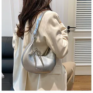 Silver metallic crossbody dumpling bag with bead bow decoration shown on a model