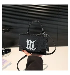 Detailaufnahme der schwarzen Kroko-Lackledertasche mit silbernem gotischem Logo-Detail