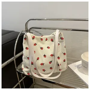 Détail de la texture du cabas en velours côtelé blanc cassé aux motifs fraises rouges