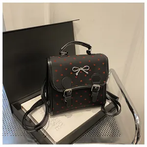 Close-up of mini backpack with red heart patterns and silver metallic bow detail