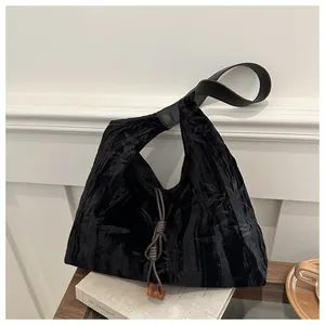 Close-up of black canvas tote bag with bamboo patterns and amber pendant on a wooden table