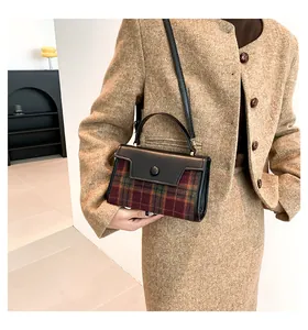 Détail d'un sac à bandoulière à carreaux avec rabat en cuir noir sur tenue kaki