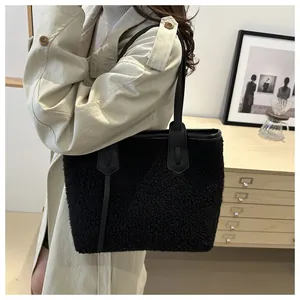 Détail d'un grand sac cabas en peluche noire avec anses en cuir sur un trench-coat beige
