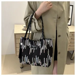 Detail of black tote bag with colorful geometric embroidery and black tassel charm