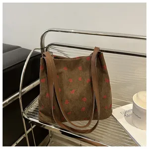Détail du sac cabas en velours côtelé avec imprimés fraises et bandoulières en cuir