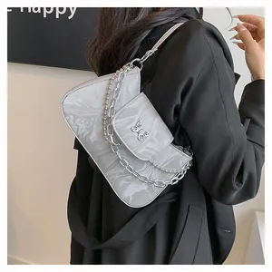 Detail of grey marble pattern shoulder bag with a metal butterfly buckle and chain strap