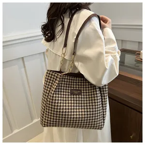 Détail du sac cabas en pied-de-poule avec bandoulière en cuir et chaîne dorée