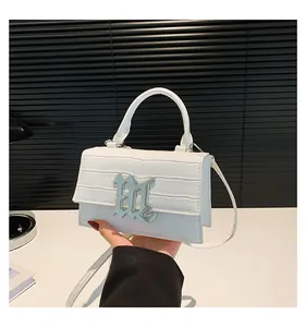 Detail einer weißen Handtasche mit Krokodilmuster und gotischem silbernen Metallverschluss