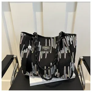 Close-up of black tote bag featuring colorful wavy embroidery and braided handles