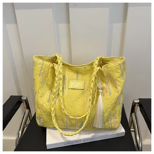 Macro shot of yellow embossed tote bag featuring multicolored zigzag stitching and tassels