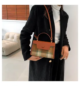 Détail du sac bandoulière vintage en cuir marron et tissu à carreaux avec boucle ronde