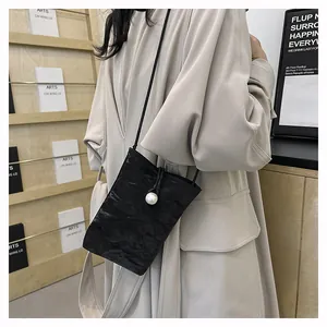 Détail du sac de téléphone plissé noir avec grande perle et fine bandoulière réglable