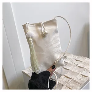 Détail du mini sac bandoulière blanc plissé avec bouton perle et pompon décoratif